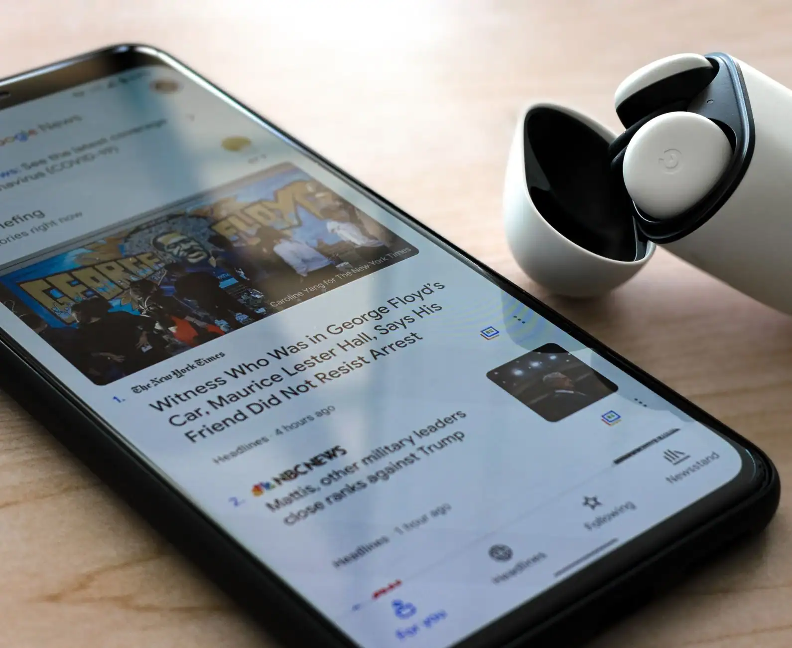 Smartphone affichant une application d'actualités à l'écran, posé sur une table en bois
