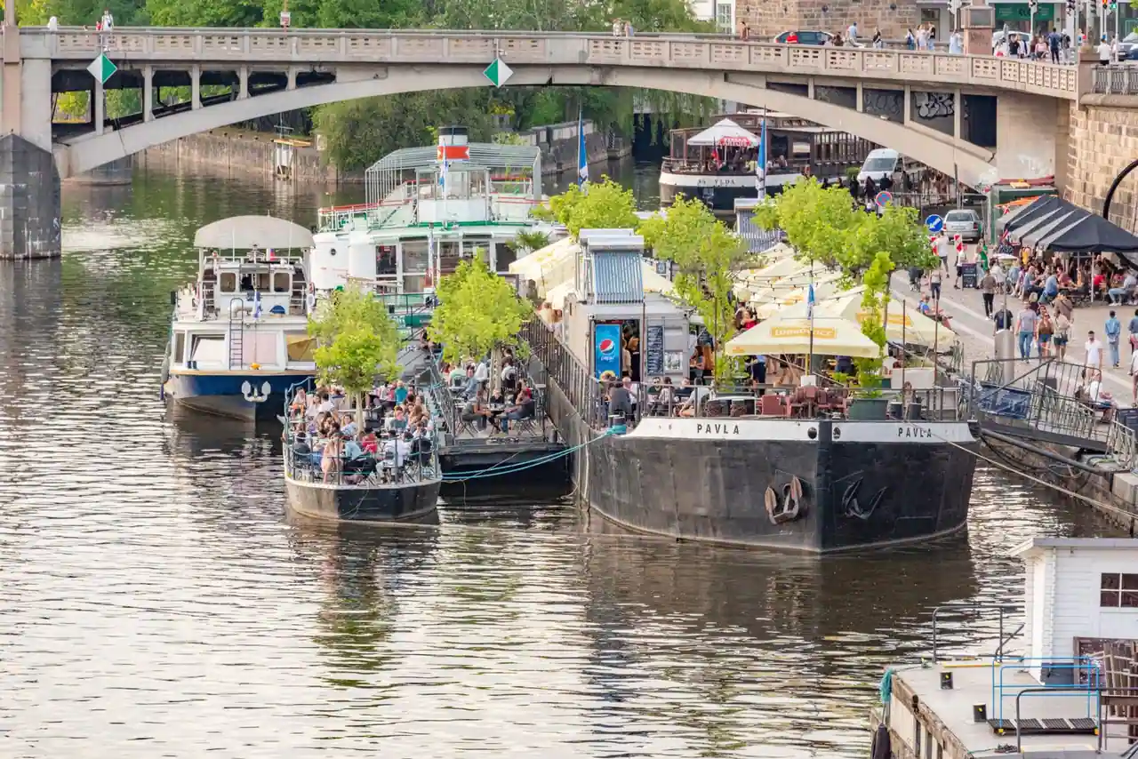 Péniches reconverties en terrasses flottantes, amarrées le long d'un quai animé