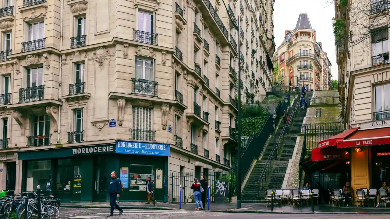 Scène de rue à Montmartre : immeubles anciens, commerces et escalier typique de la butte.