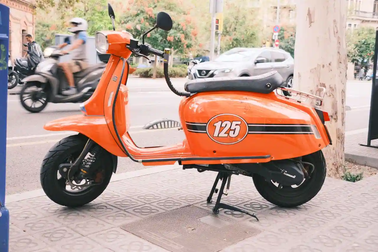 Scooter urbain orange stationné sur un trottoir, deux-roues compact dans une rue de ville
