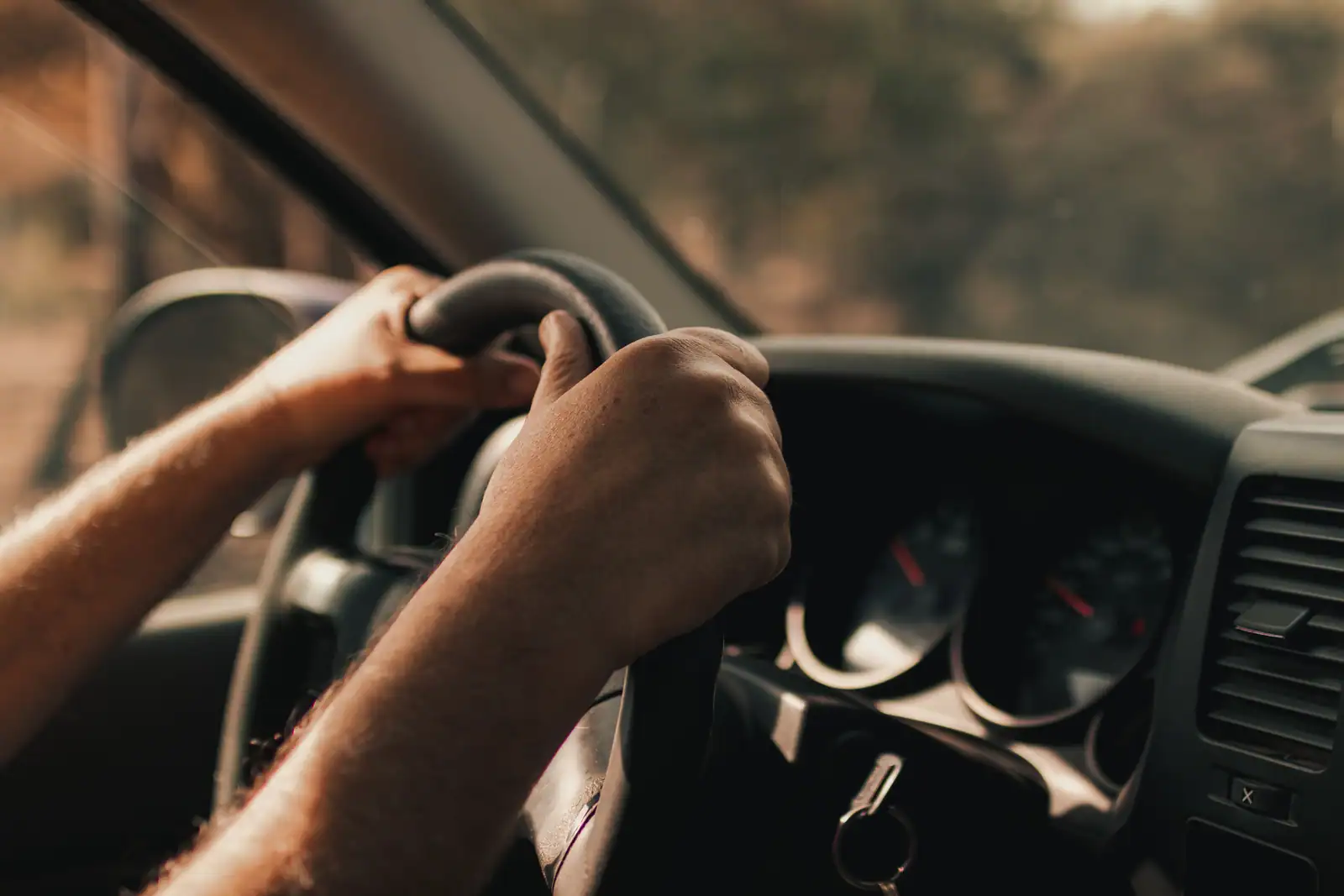 Mains d'un conducteur sur le volant d'une voiture, tableau de bord visible pendant un essai sur route
