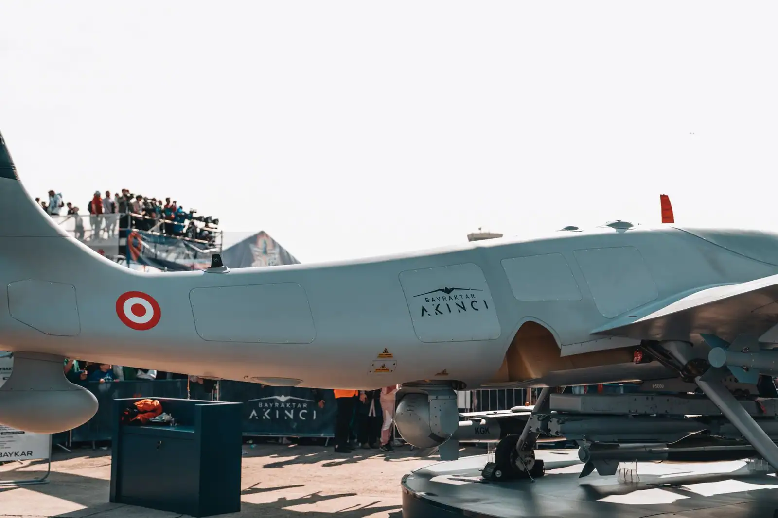 Drone militaire de combat exposé lors d'un salon aéronautique, munitions visibles sous l'aile.