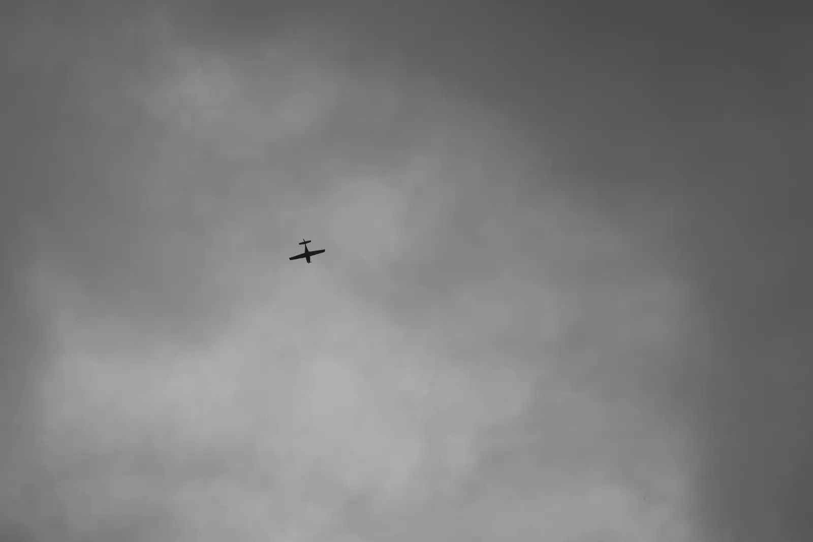 Silhouette d'un aéronef à voilure fixe dans un ciel nuageux gris