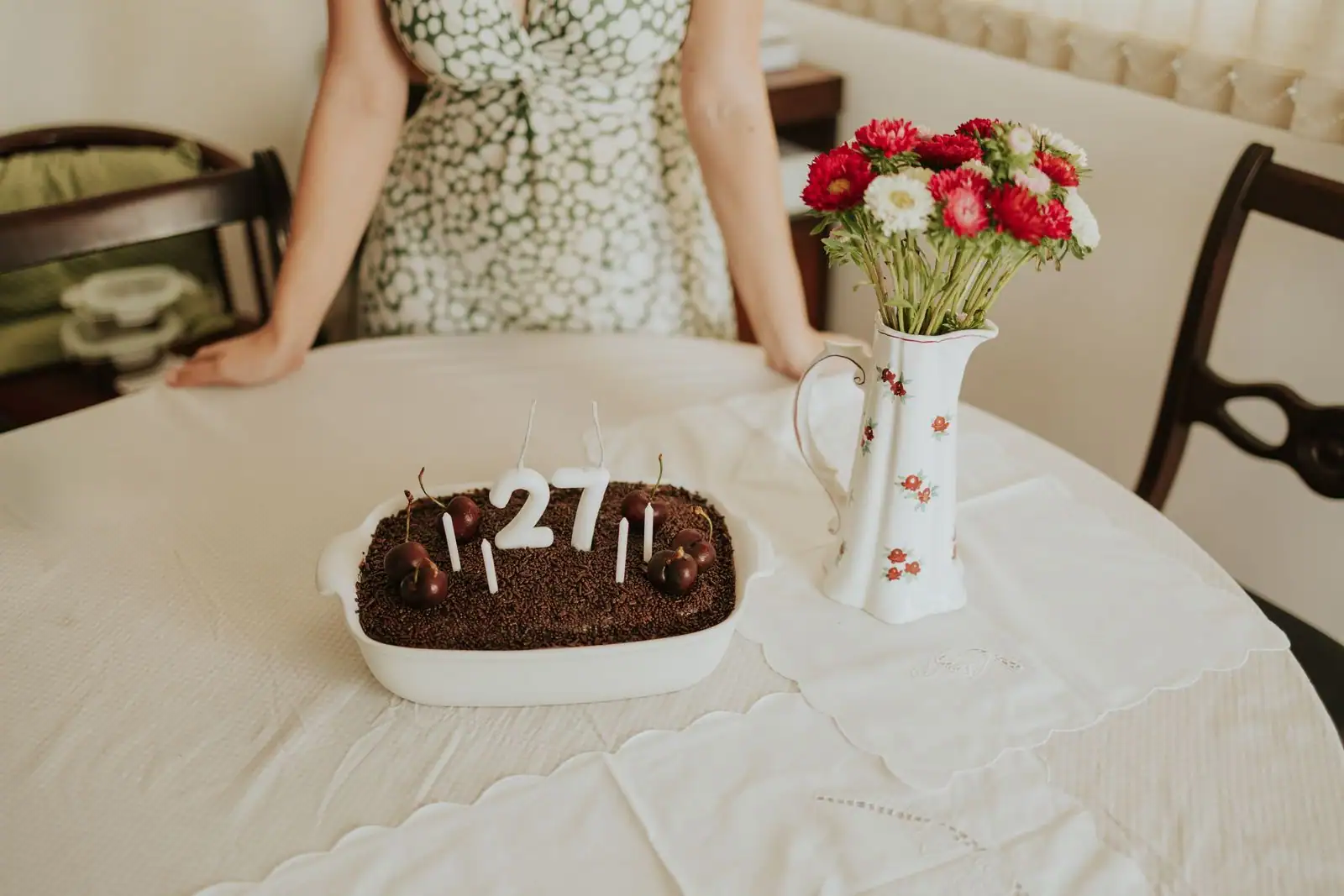 Gâteau d'anniversaire au chocolat maison garni de cerises et de bougies, posé sur une table.