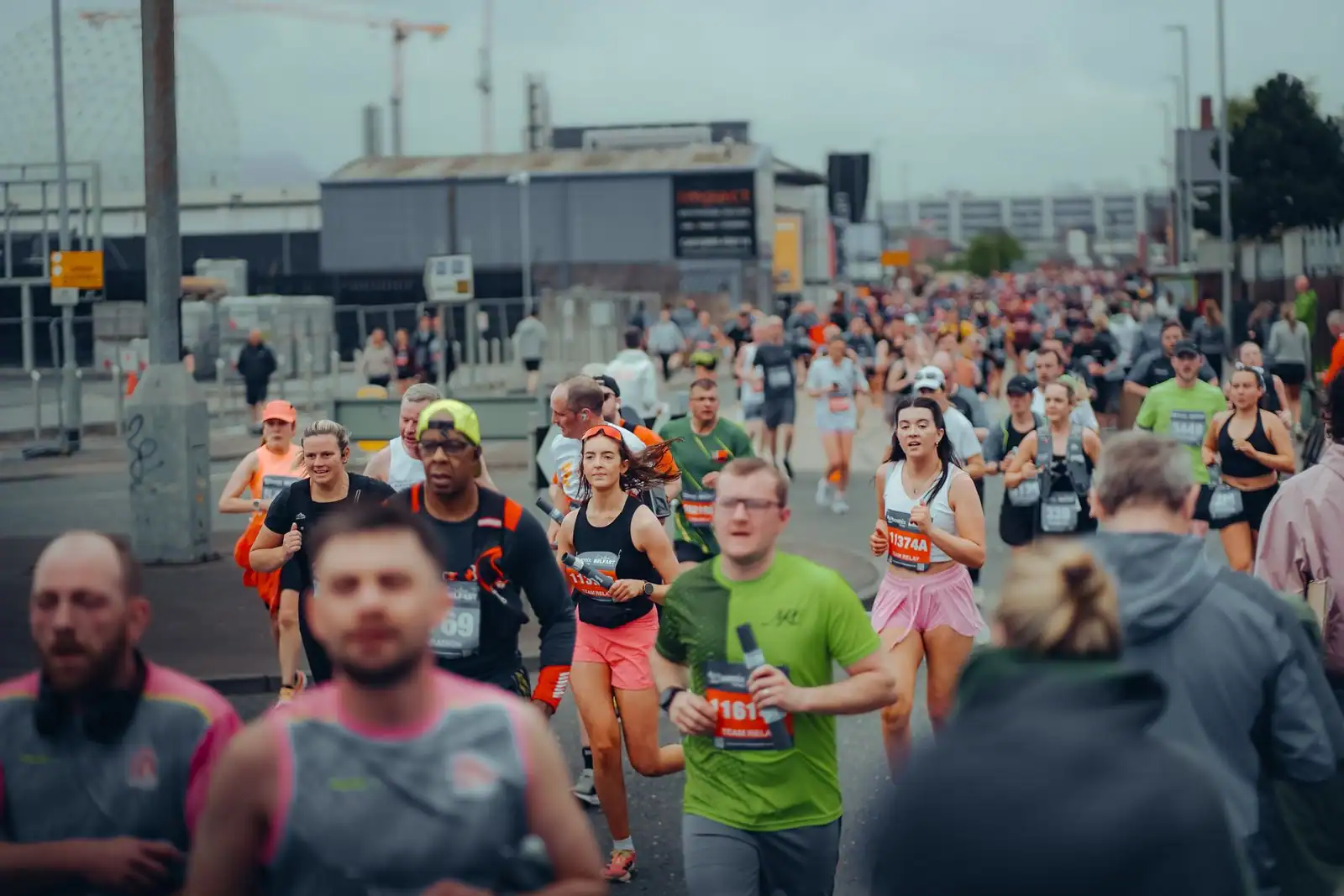 Nombreux coureurs en dossard sur une route lors d'une course à pied populaire.
