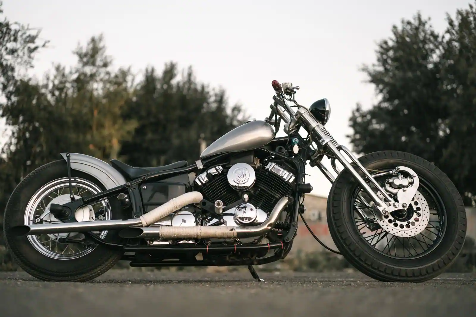 Moto custom de type cruiser au long réservoir profilé et aux chromes, garée en extérieur