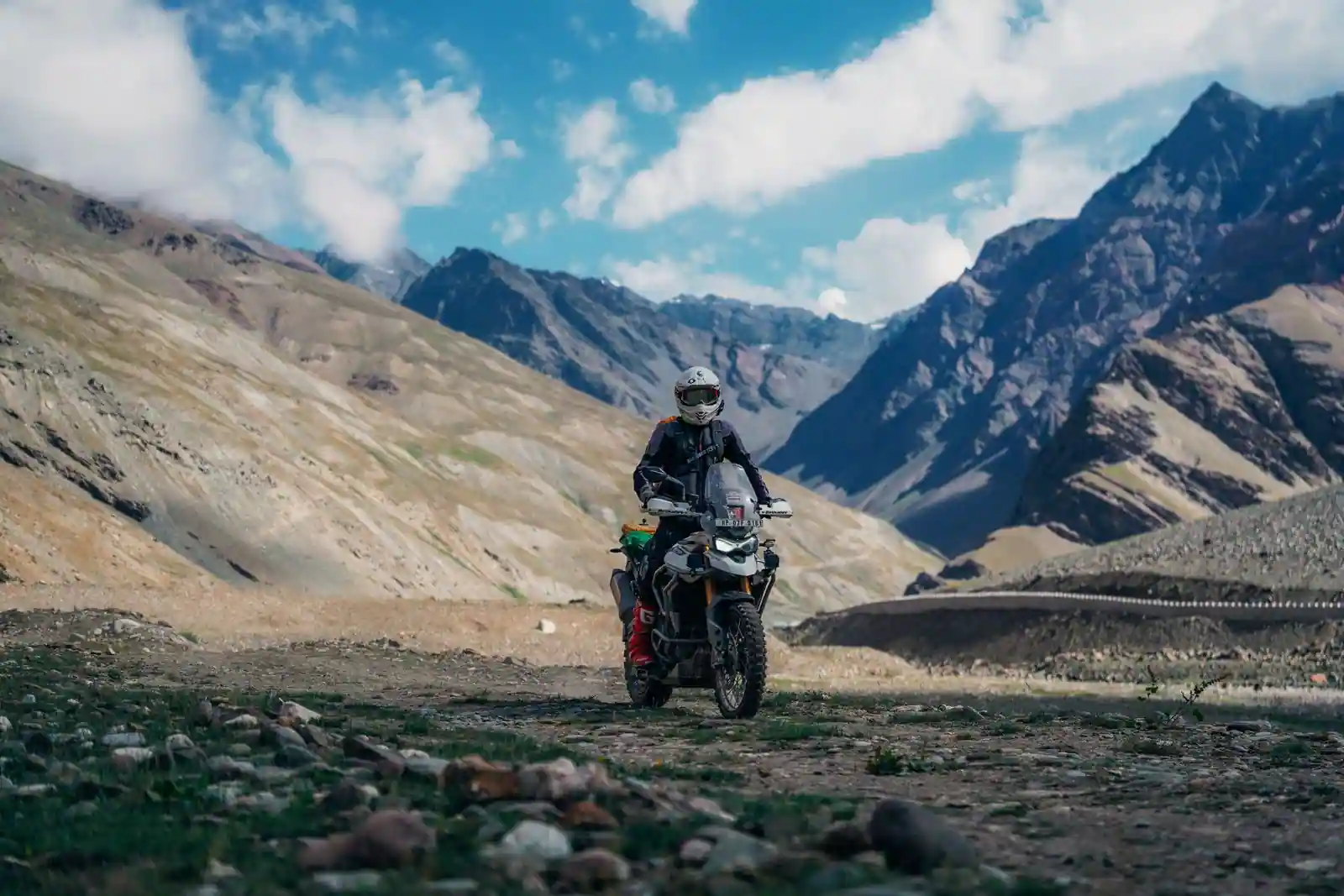 Motard sur une moto trail d'aventure chargée de bagages, sur une piste de montagne sauvage