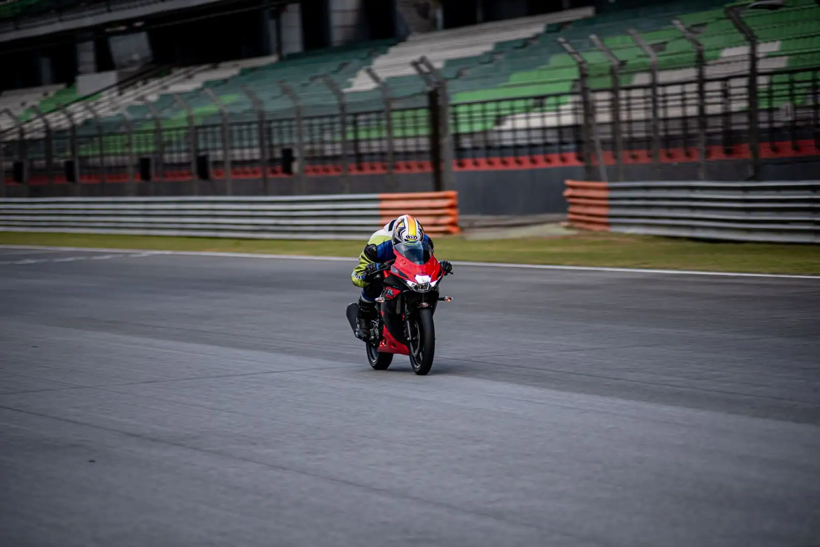 Moto sportive rouge carénée pilotée sur un circuit, le pilote penché vers l'avant en action.