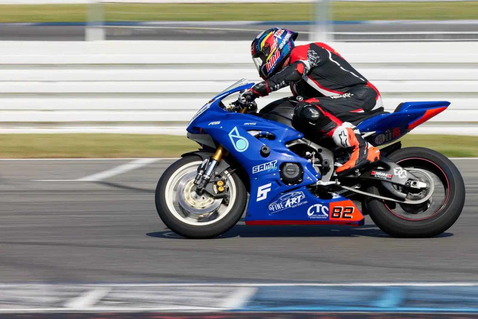 Pilote en combinaison penché sur une moto sportive carénée lancée sur un circuit