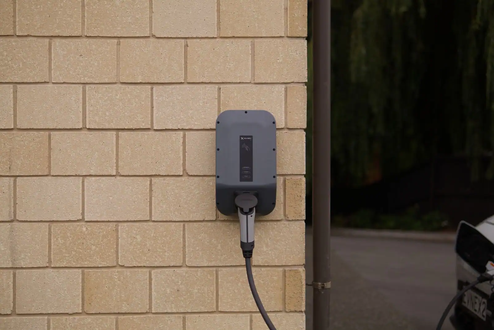 Borne de recharge murale pour véhicule électrique, câble de charge branché le long d'un mur