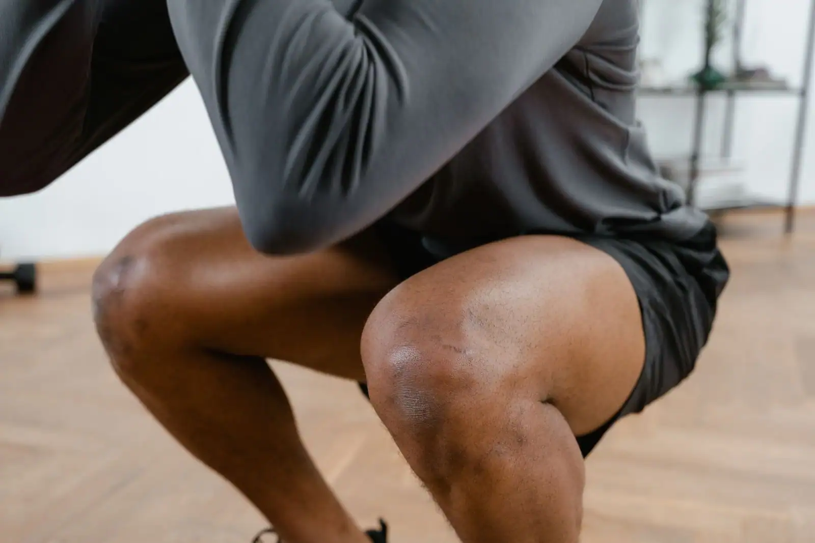 Cuisse et genou d'un sportif en pleine flexion de squat, muscles du devant de la jambe sollicités.