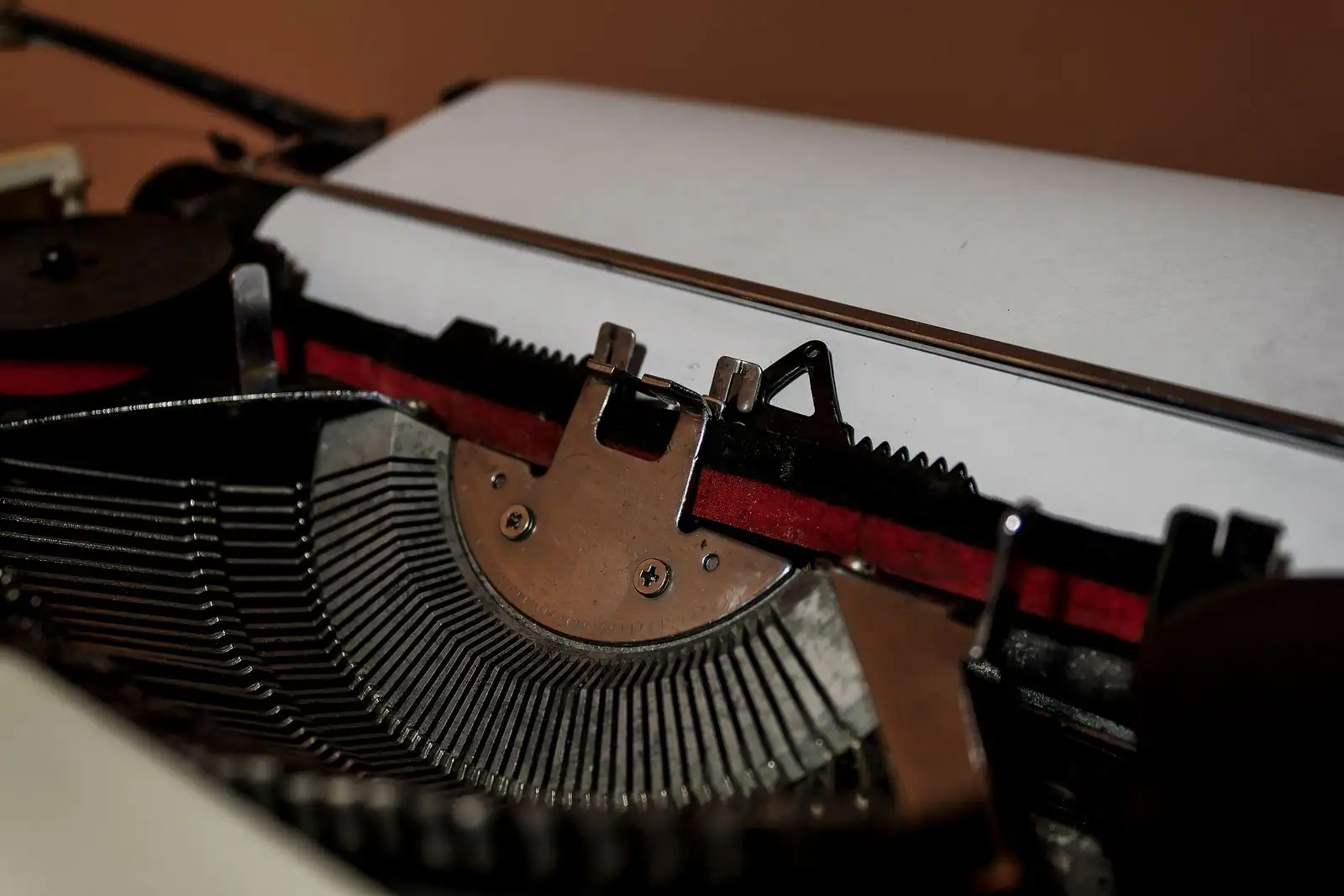 Mécanisme d'une machine à écrire ancienne, marteaux et feuille de papier vierge, gros plan.