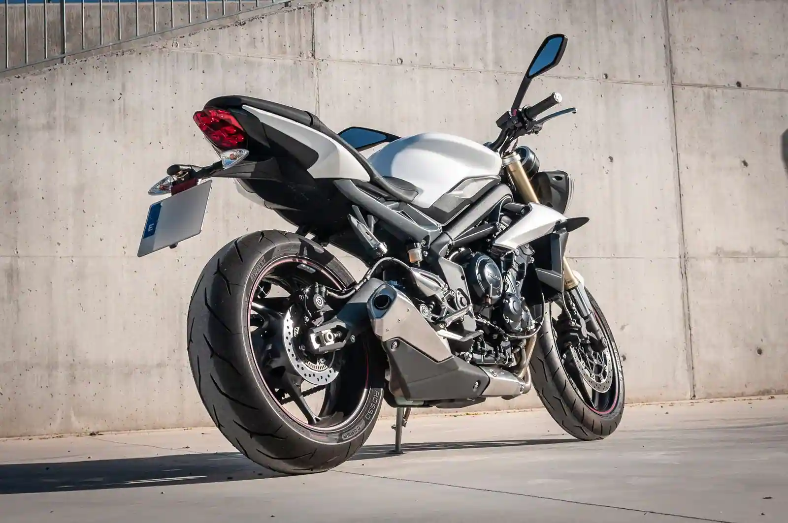 Roadster sportif sans carénage à l'arrêt contre un mur, mécanique et jante apparentes