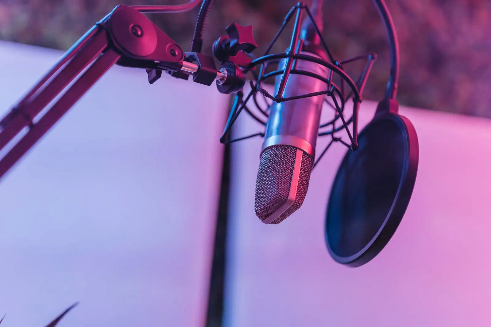 Micro de studio d'enregistrement professionnel avec filtre anti-pop, sous un éclairage coloré