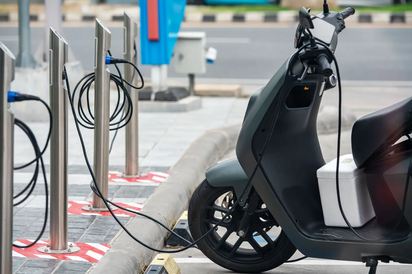 Scooter électrique moderne branché à une borne de recharge en bordure de rue, en ville