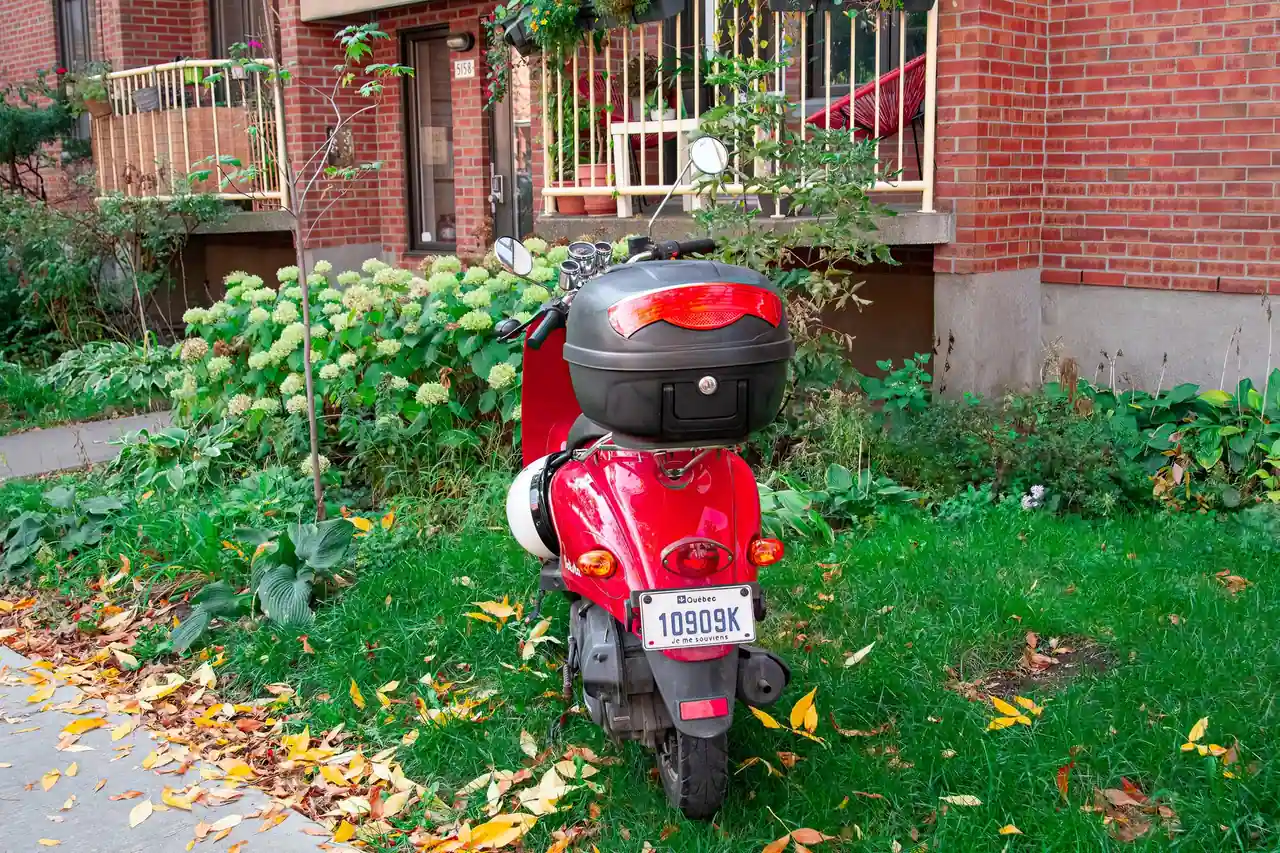 Scooter à moteur moderne avec top-case stationné le long d'un trottoir en ville