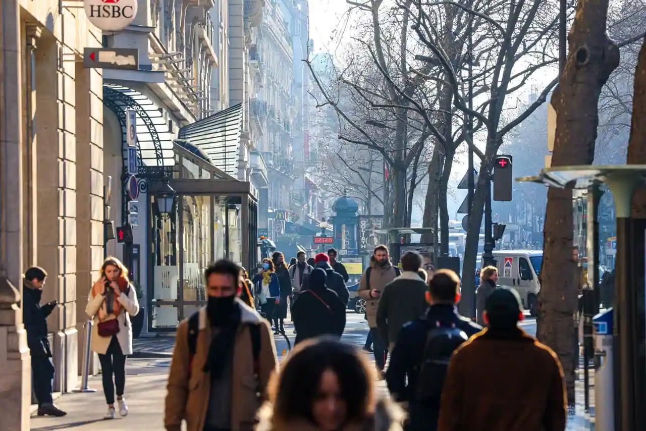 Passants sur le trottoir animé d'un boulevard de ville par une journée ensoleillée d'hiver, ambiance de sortie.