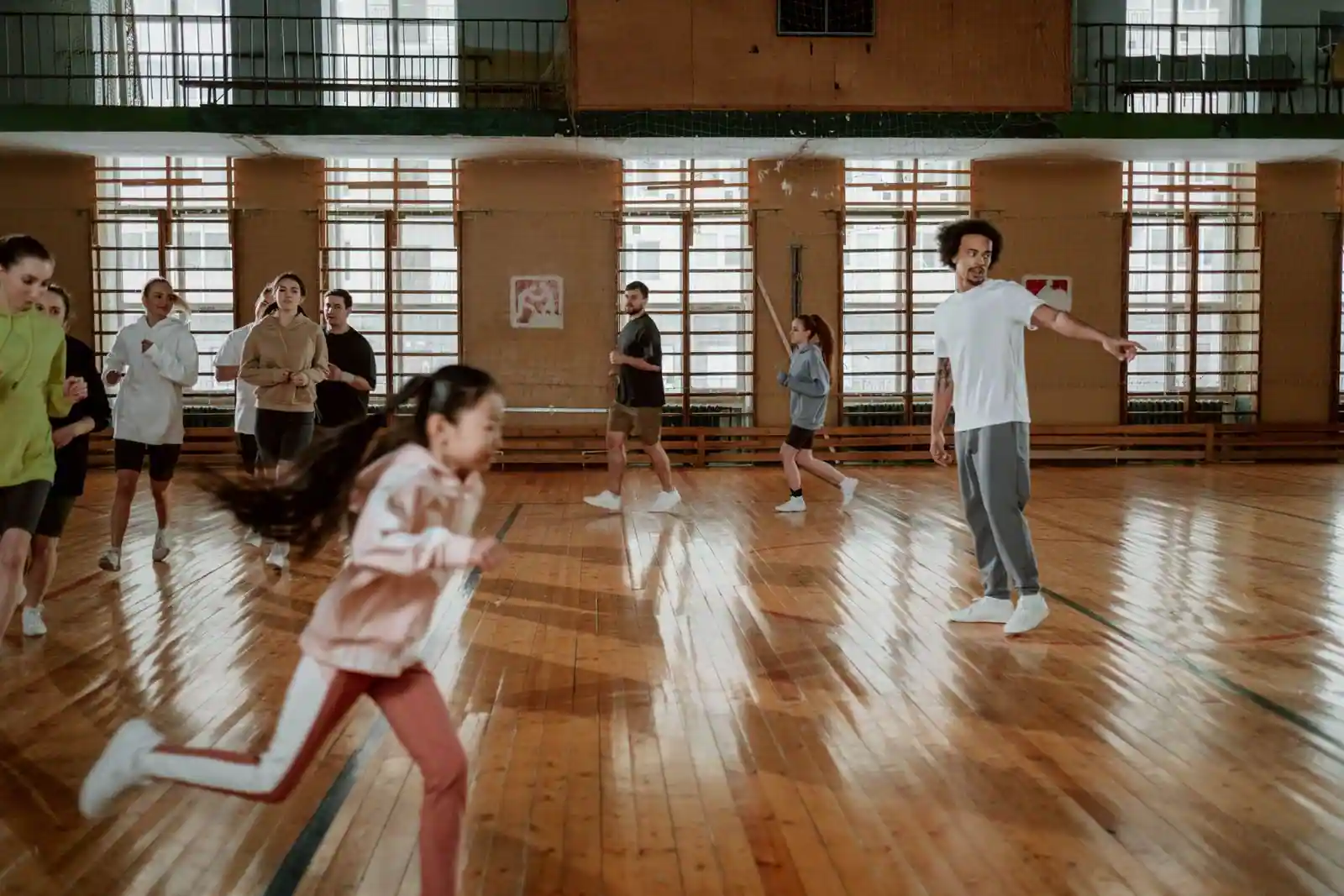 Groupe de pratiquants de tous âges en entraînement dans une salle de sport au parquet, illustrant la pratique en club