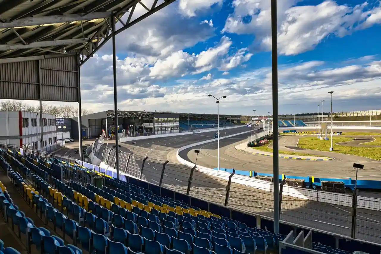 Circuit de sport automobile avec ses tribunes vides sous un ciel dégagé, vu depuis les gradins.