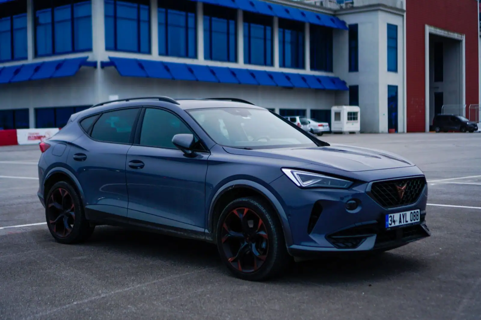 SUV sportif compact au profil de coupé surélevé, photographié de trois quarts avant sur un parking dégagé