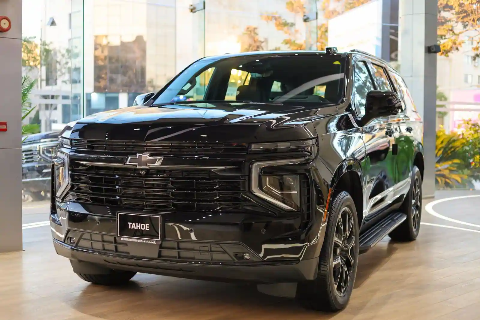 Un grand SUV Chevrolet Tahoe noir, vu de trois quarts avant dans un hall d'exposition