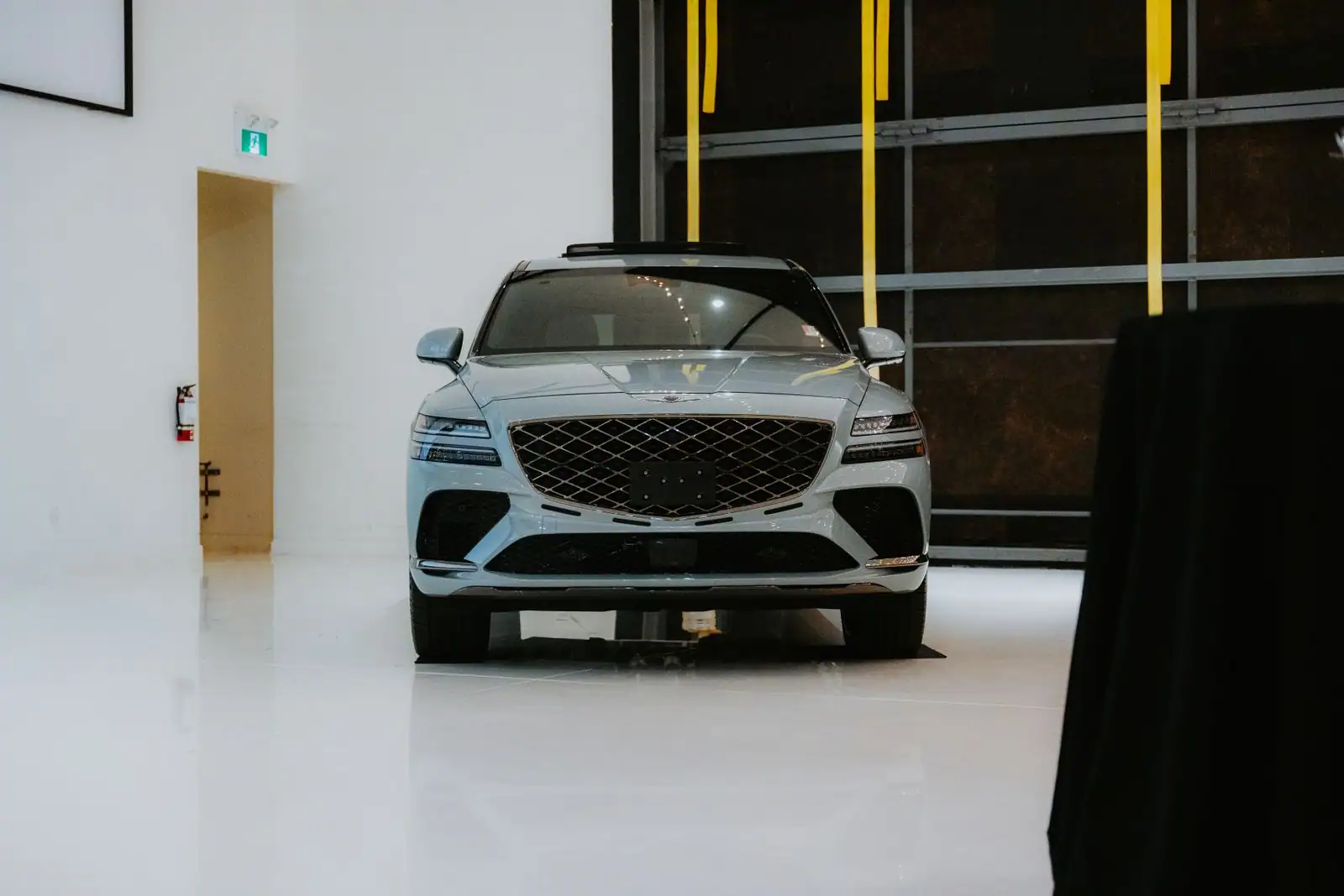 Grand SUV de luxe gris au design moderne, vu de face dans un espace d'exposition épuré.