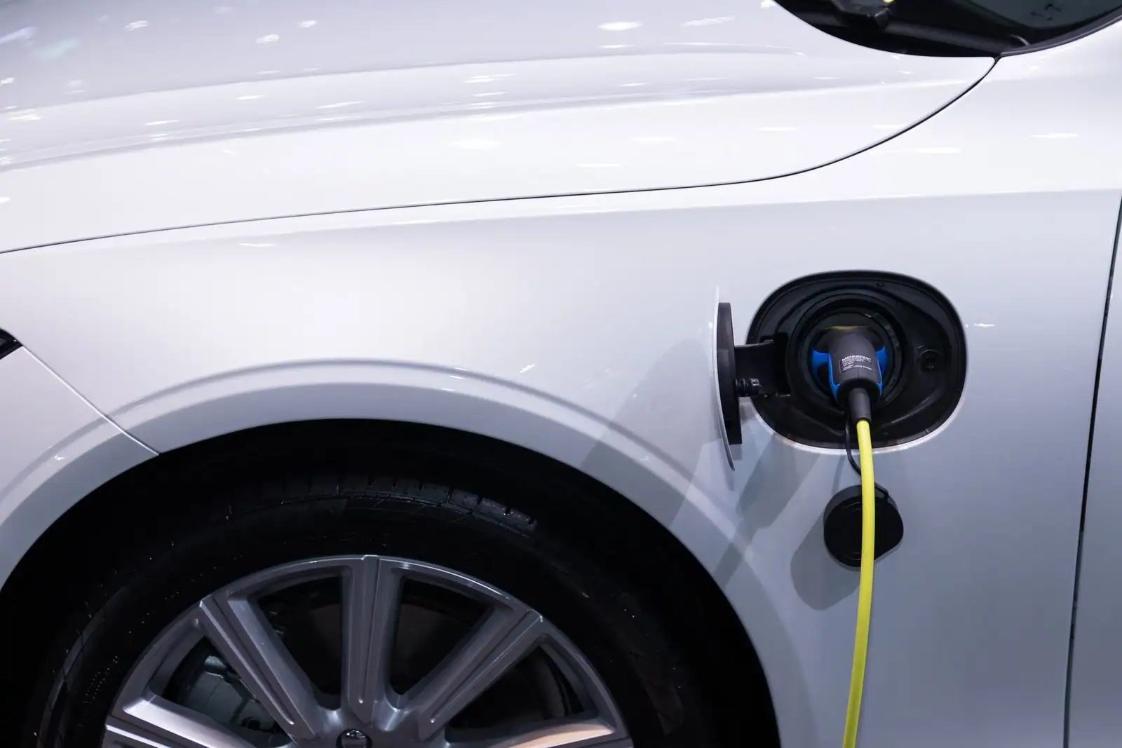 Gros plan sur la trappe de recharge d'un véhicule électrique avec le câble branché.