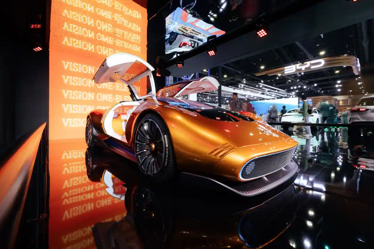 Concept-car futuriste doré aux lignes fuselées, porte papillon ouverte, exposé sur un salon automobile