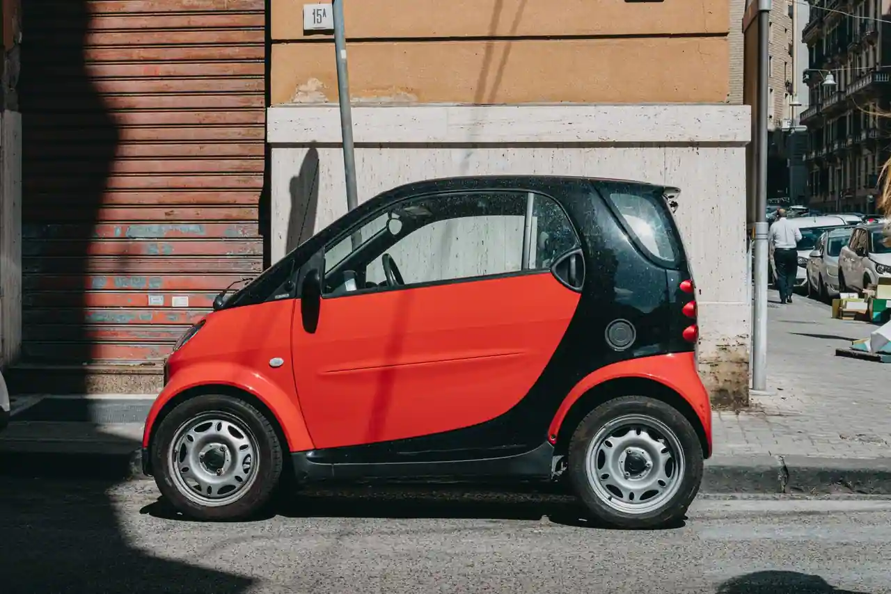 Voiture compacte stationnée le long d'une rue italienne bordée de façades anciennes, en plein jour