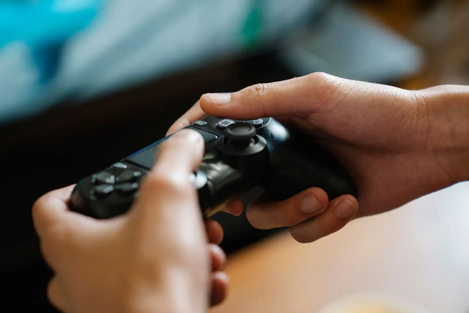 Gros plan sur une manette de console noire tenue à deux mains par un joueur pendant une partie