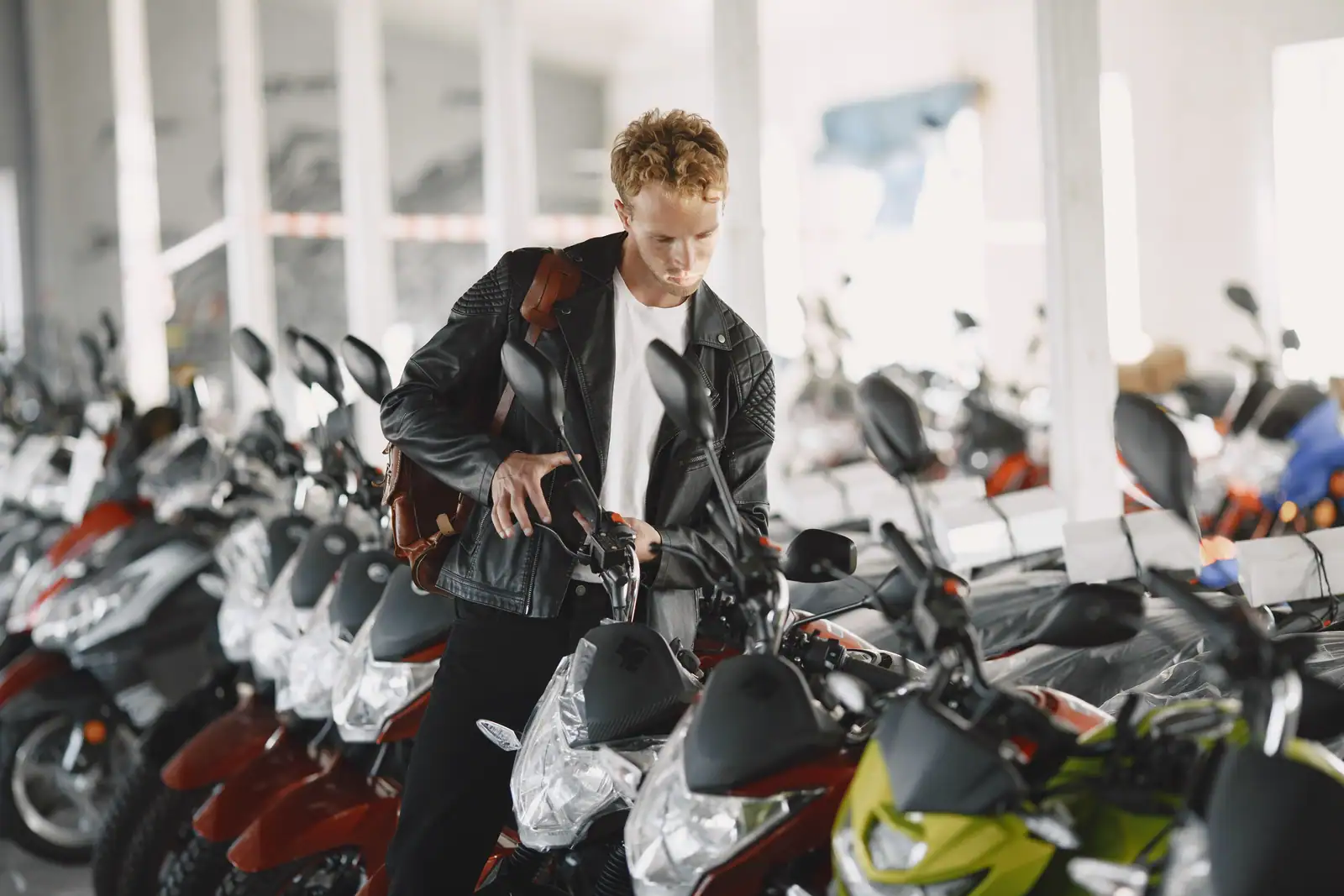 Un client examine une rangée de motos neuves, selles encore sous film, dans le hall d'une concession