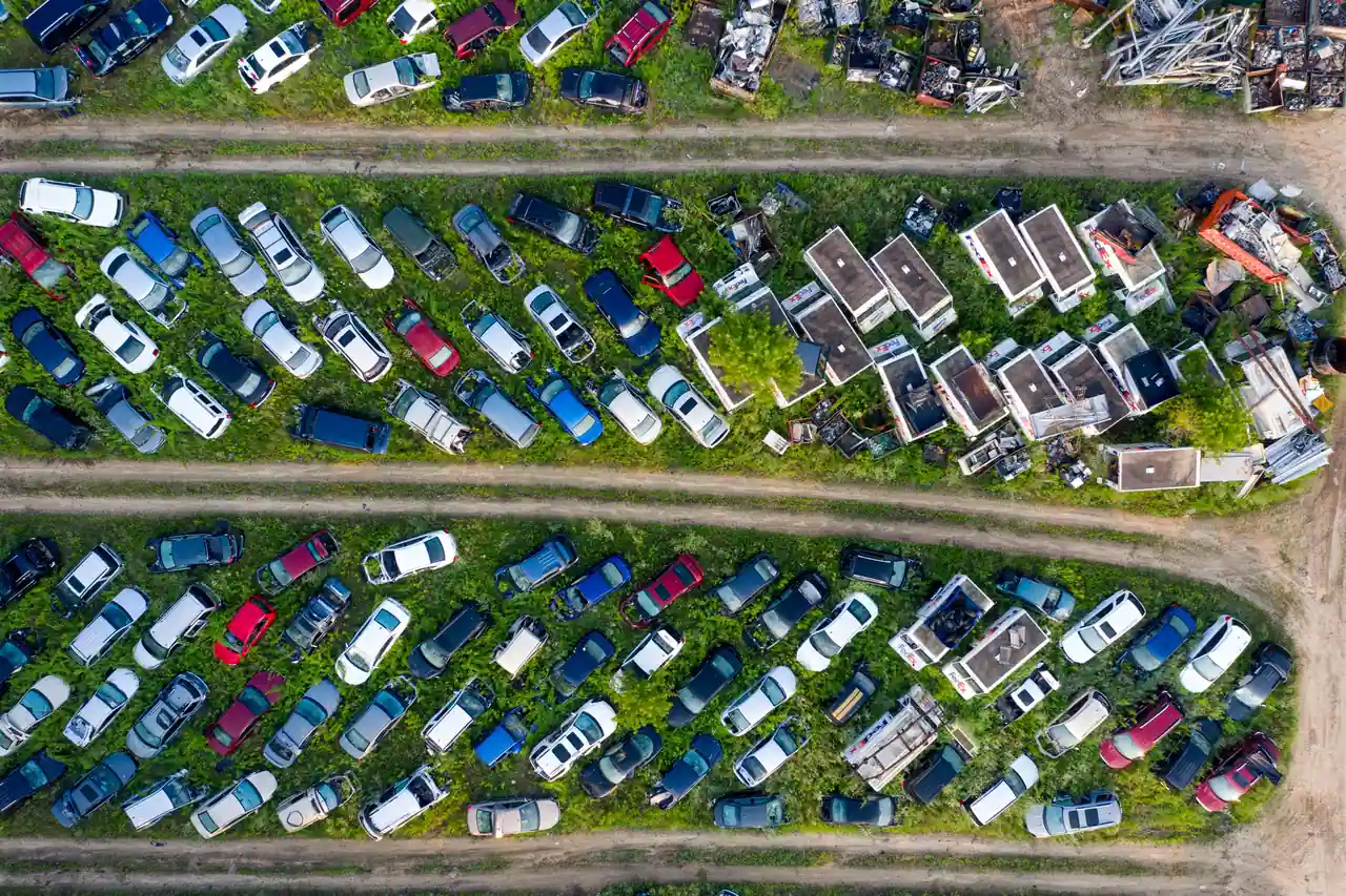 Vue aérienne de véhicules hors d'usage alignés en rangées sur un site de recyclage automobile