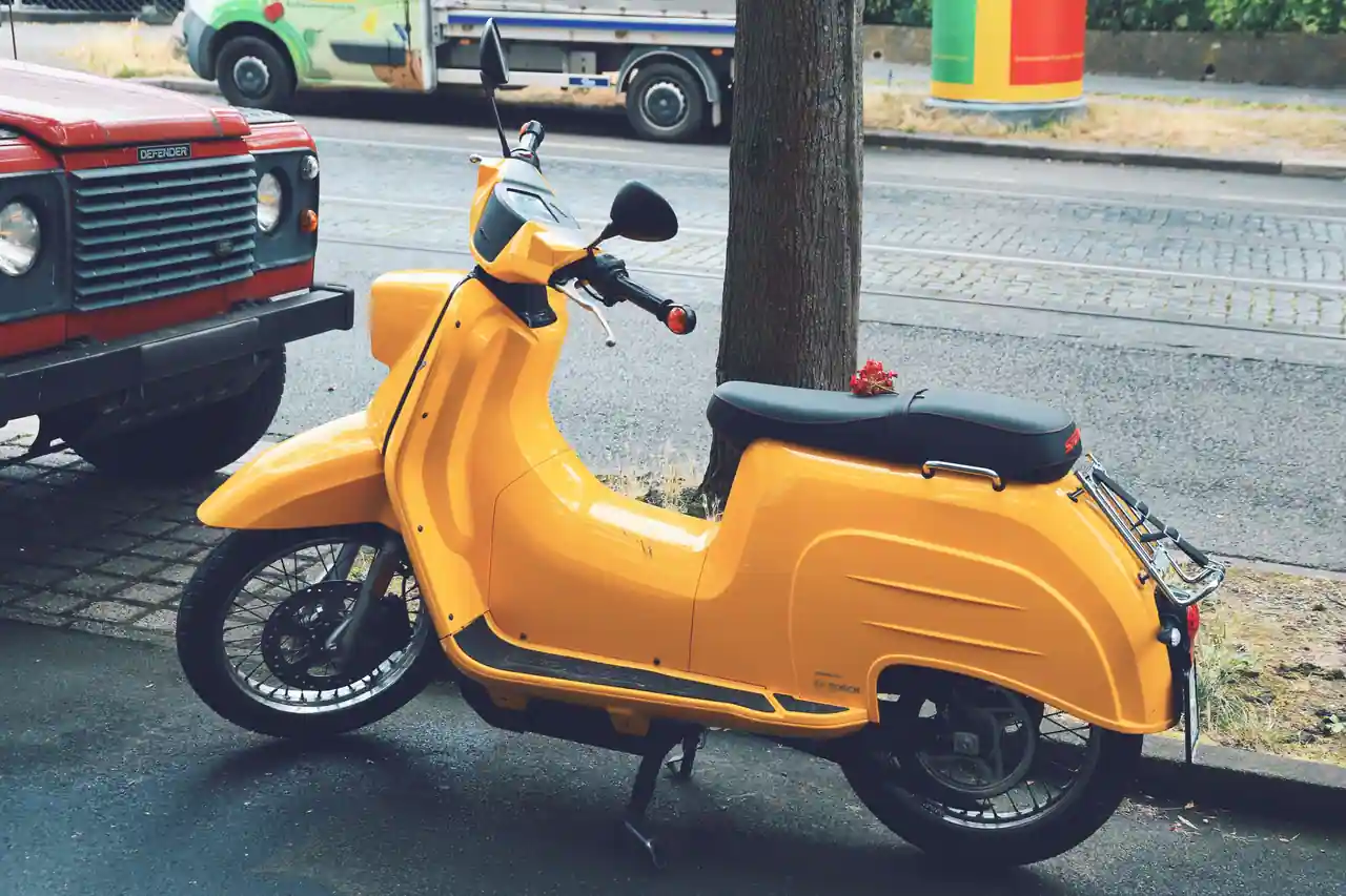Scooter compact de catégorie cyclomoteur stationné le long d'un trottoir dans une rue de ville
