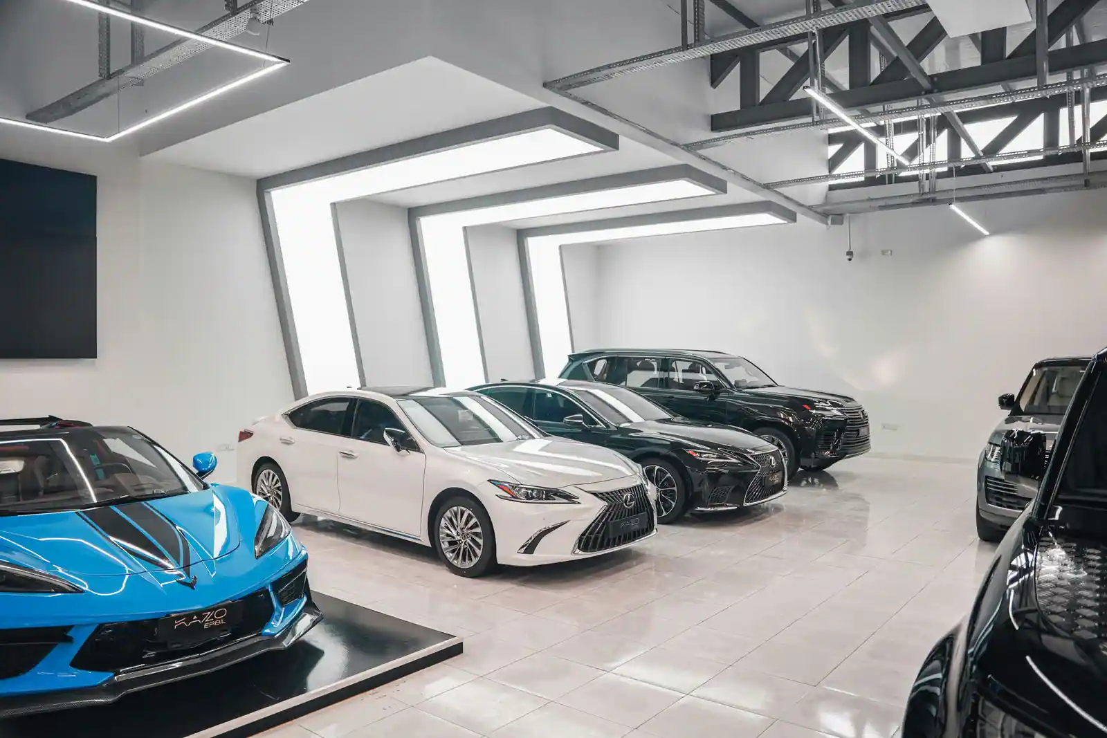 Berlines et SUV haut de gamme alignés dans le hall d'exposition d'une concession automobile.