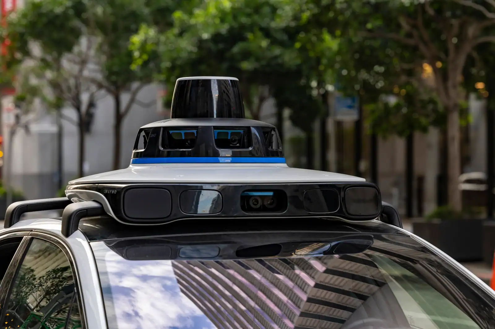 Bloc de capteurs et de caméras monté sur le toit d'un véhicule autonome, dans une rue arborée.