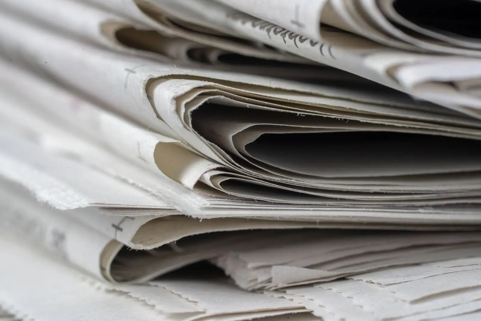 Pile de journaux imprimés vue de près, les tranches pliées empilées les unes sur les autres.