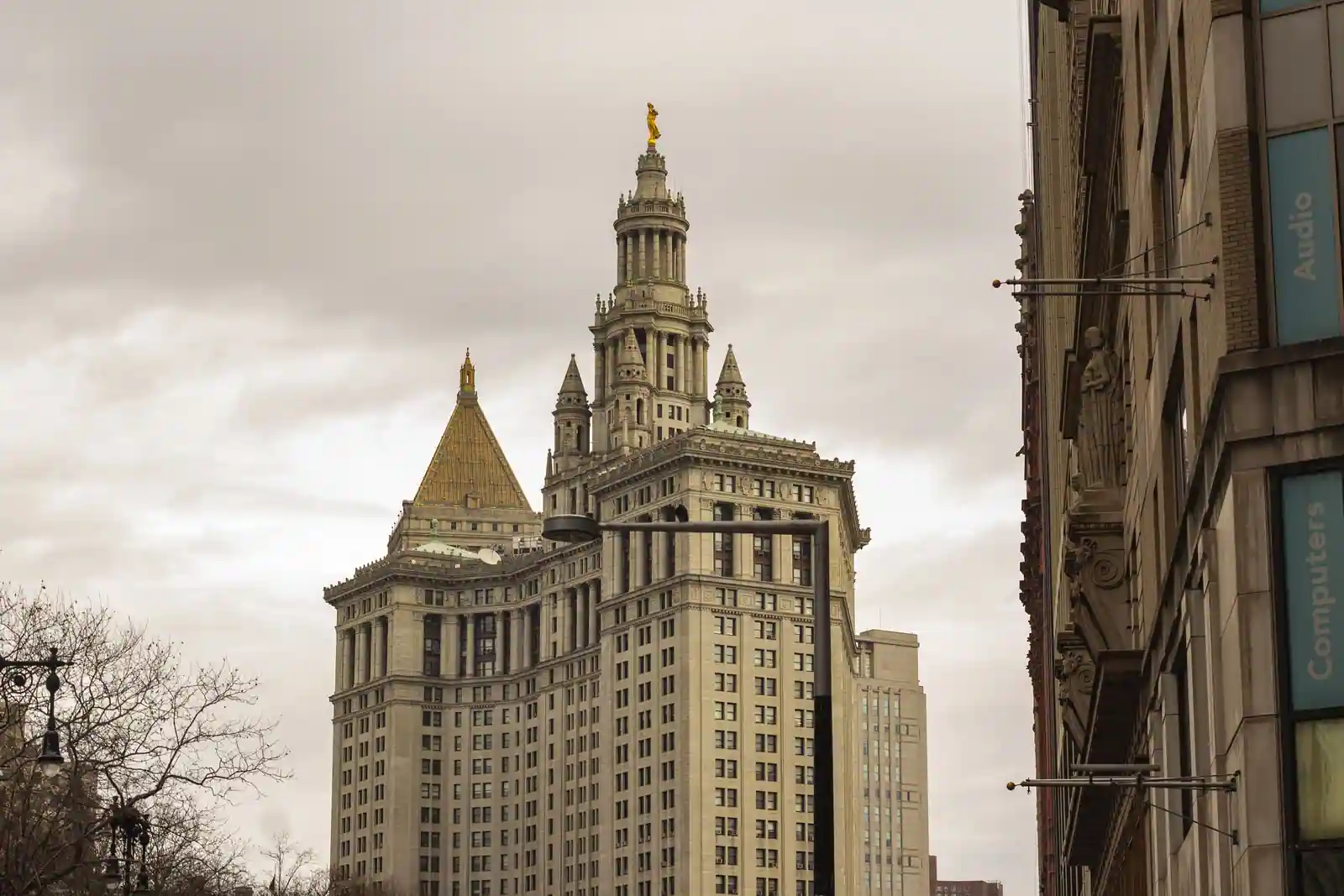 Le bâtiment municipal de Manhattan et sa tour à colonnade, vu depuis la rue par temps couvert.