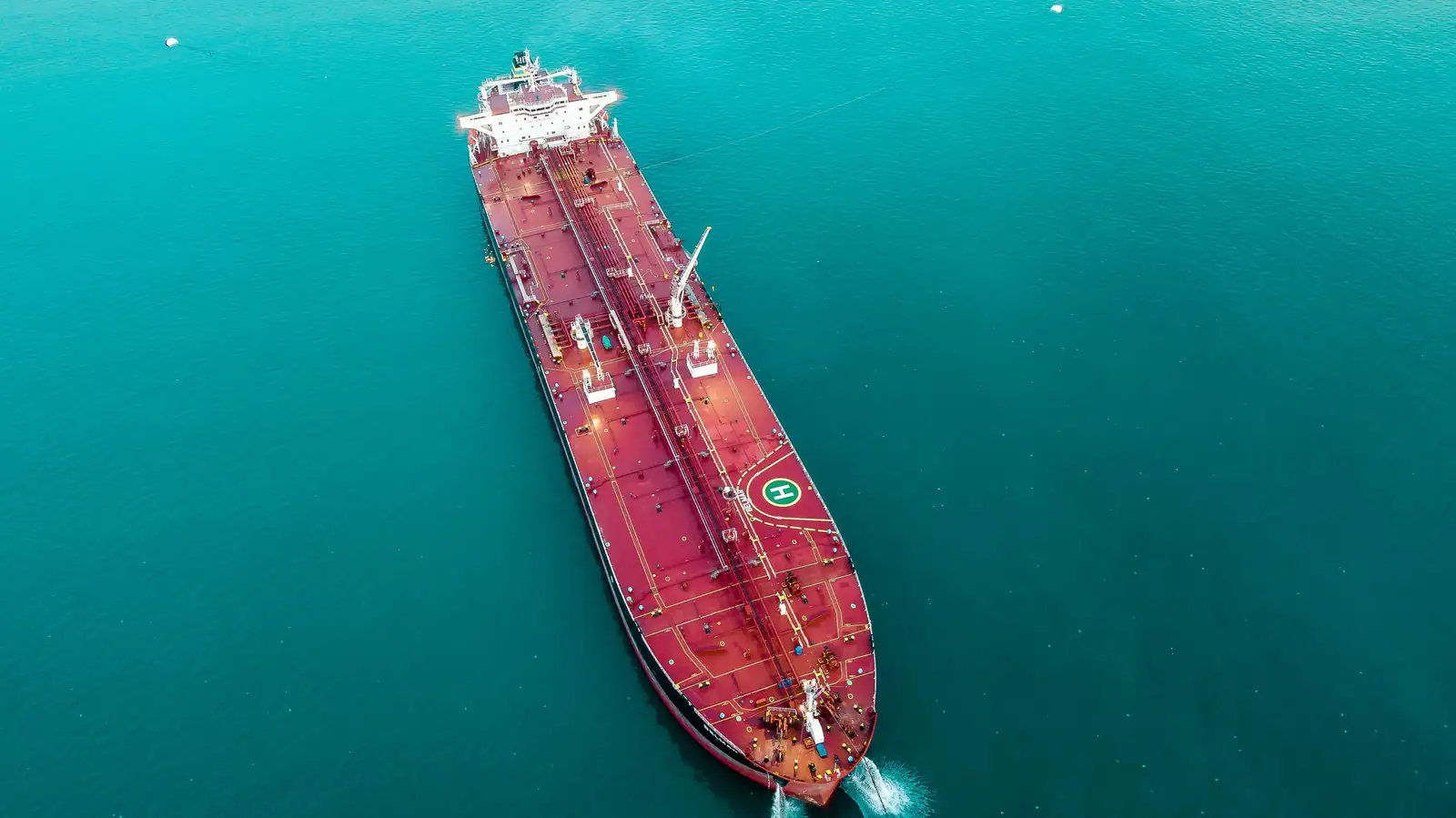 Vue aérienne d'un pétrolier rouge faisant route en pleine mer, sans nom ni pavillon visibles du ciel