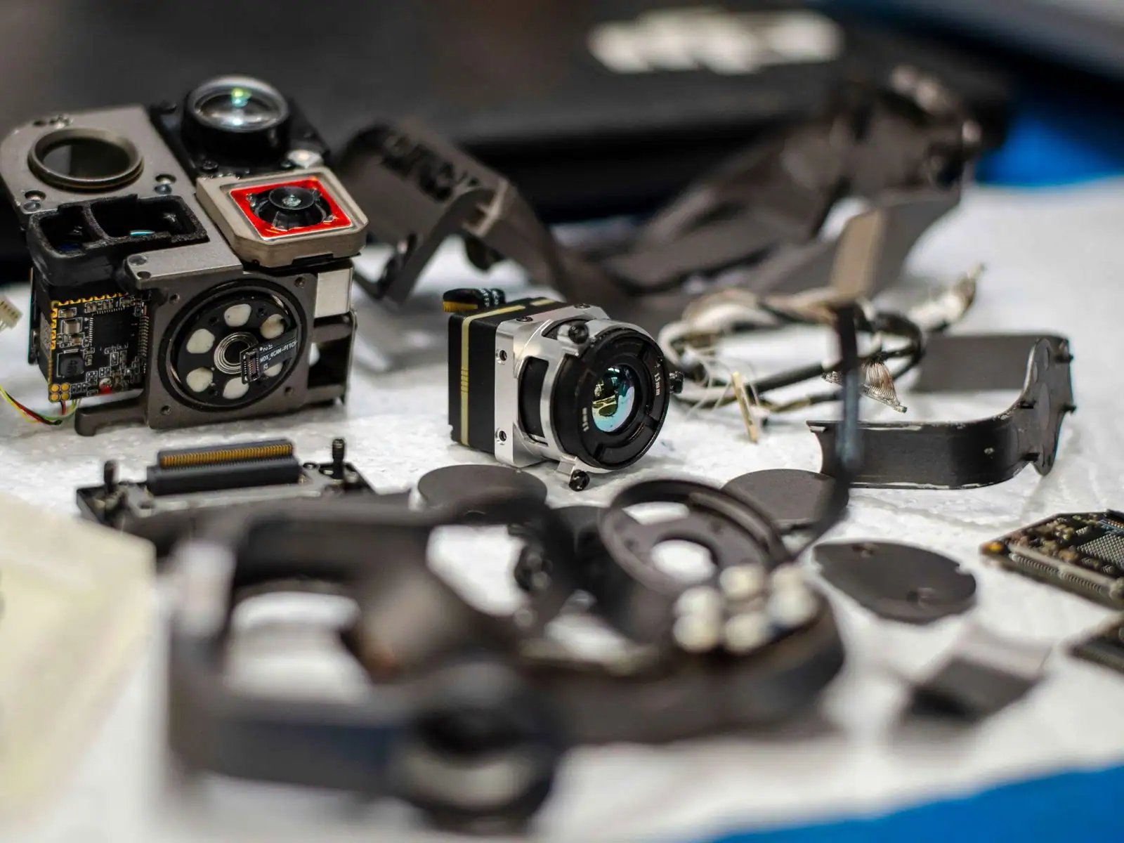 Pièces détachées d'un drone posées sur un plan de travail : module caméra, cartes électroniques et bras.