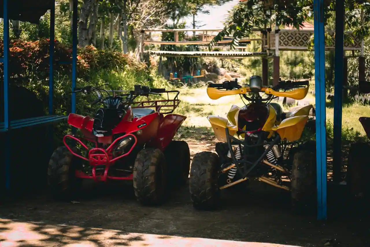 Deux quads de loisir garés côte à côte sous un abri, sans l’équipement routier des modèles homologués.