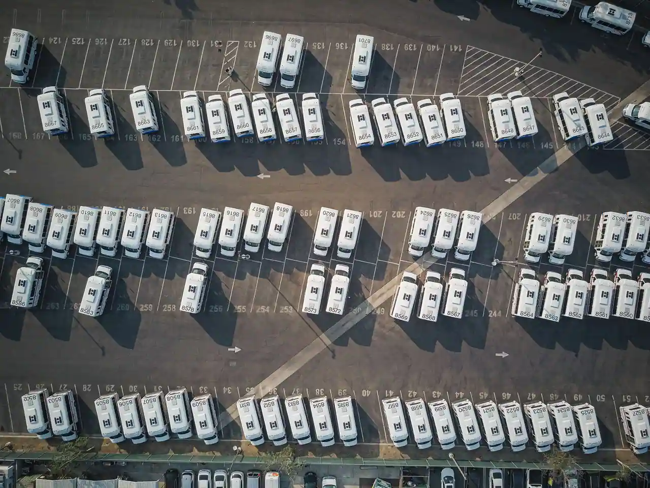 Vue aérienne de dizaines de camping-cars blancs alignés en rangées sur un vaste parc de stationnement